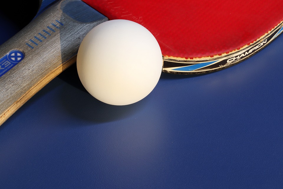 ping_pong_balle_blanche_et_raquette_rouge_sur_table_bleue